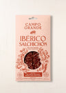 Sliced Ibérico salchichón in pink packaging with circular window showing dark red meat slices.
