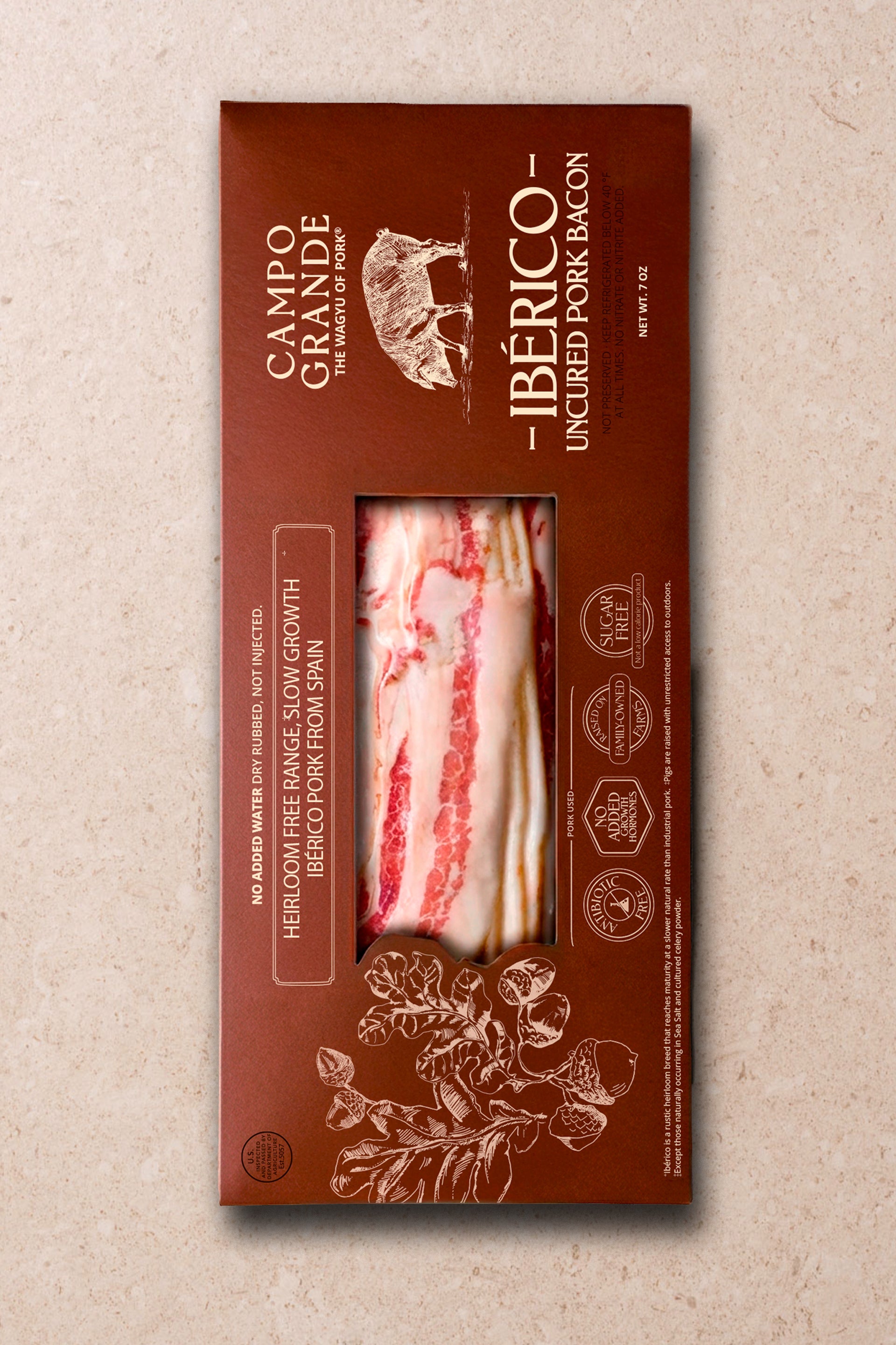 Package of sliced Ibérico uncured pork bacon with red meat and white fat visible through window on brown box.