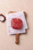 Raw wagyu tenderloin steak with fine marbling on wooden cutting board with paper and salt.