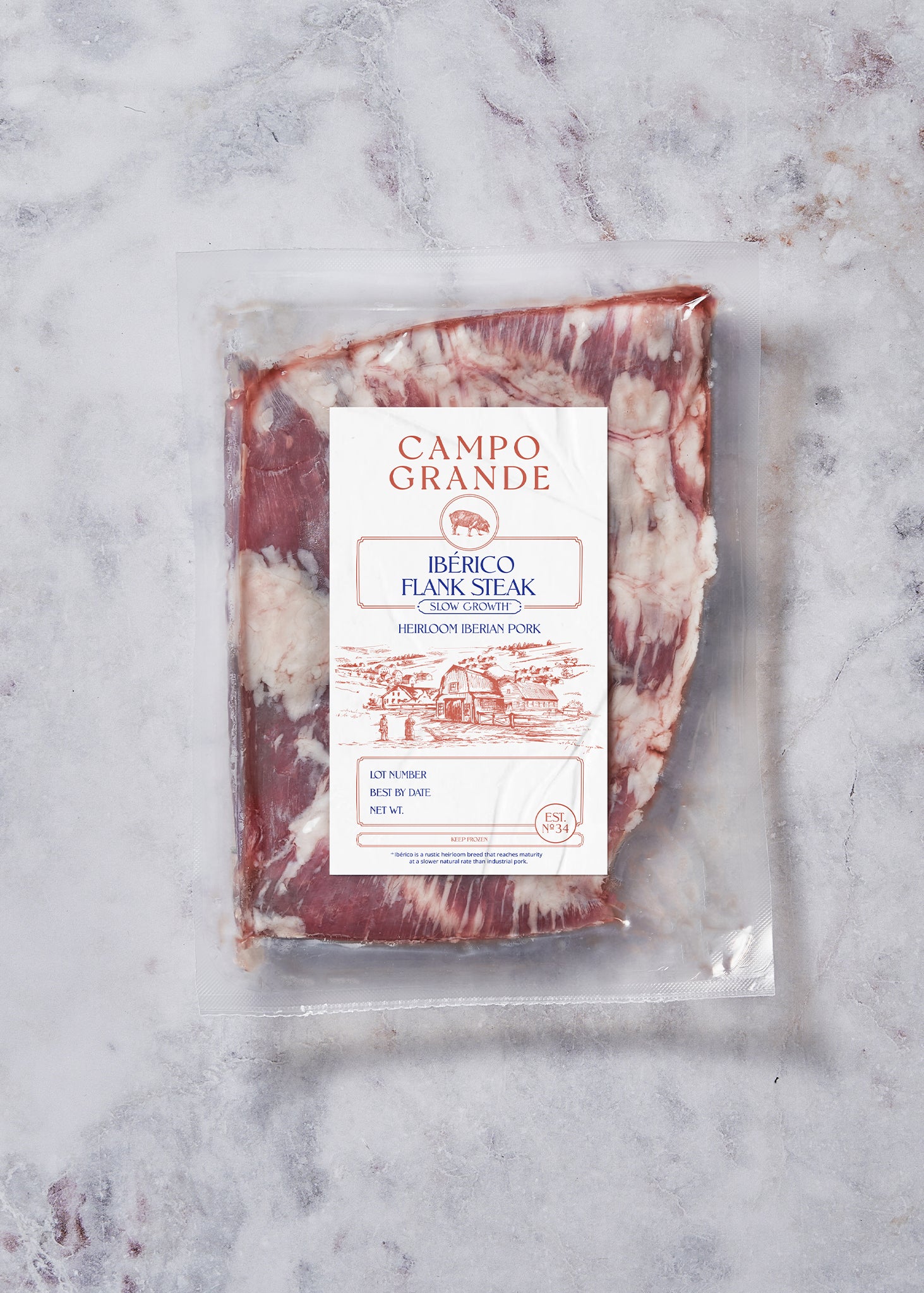 Frozen Ibérico flank steak with marbling, vacuum-sealed in plastic packaging with Campo Grande label on marble background.