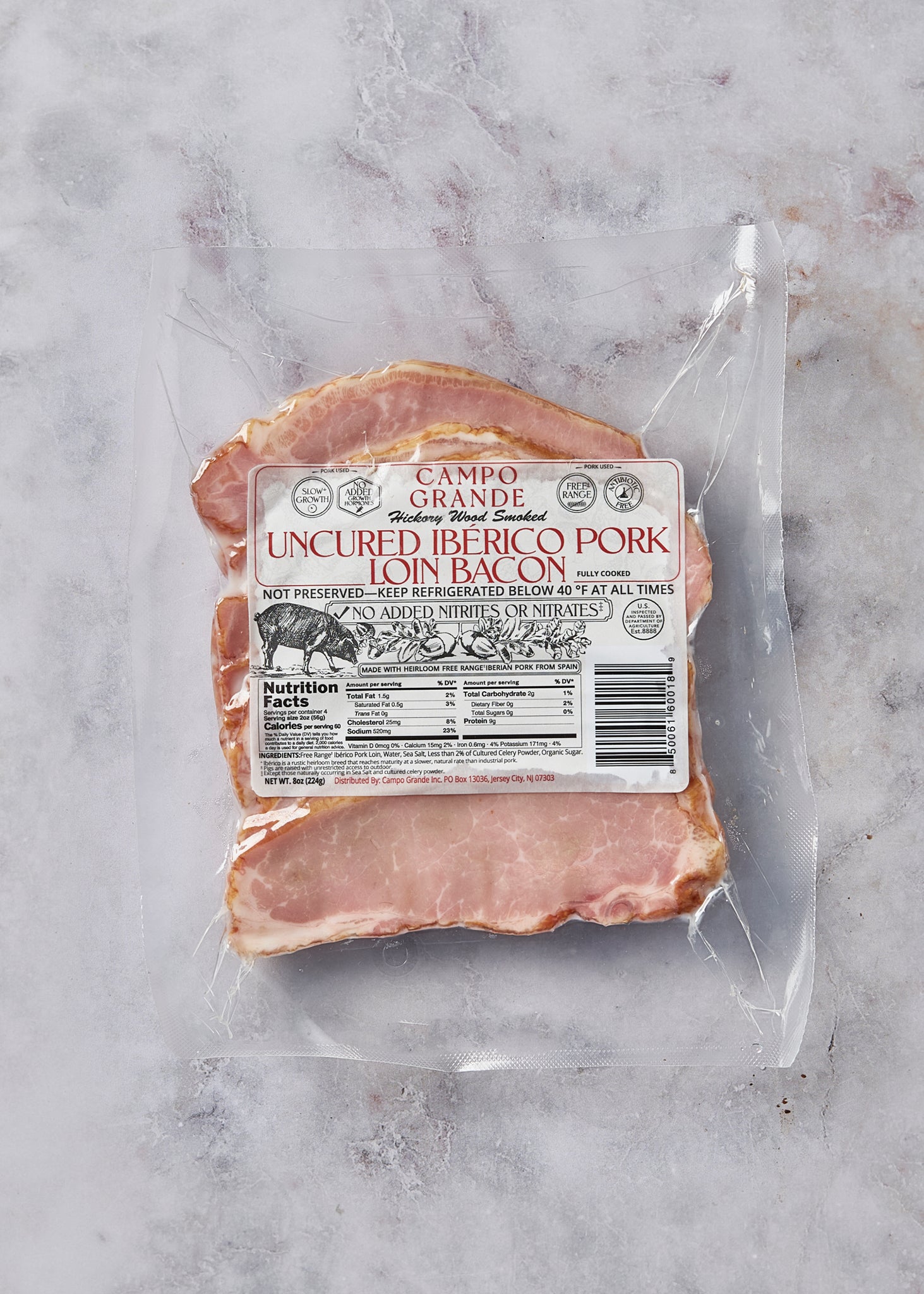 Hickory wood smoked uncured Iberico pork loin bacon package with label showing nutrition facts on gray surface.