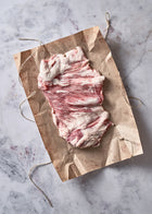 Raw Ibérico Secreto steak with marbling and fat cap on kraft paper with twine.