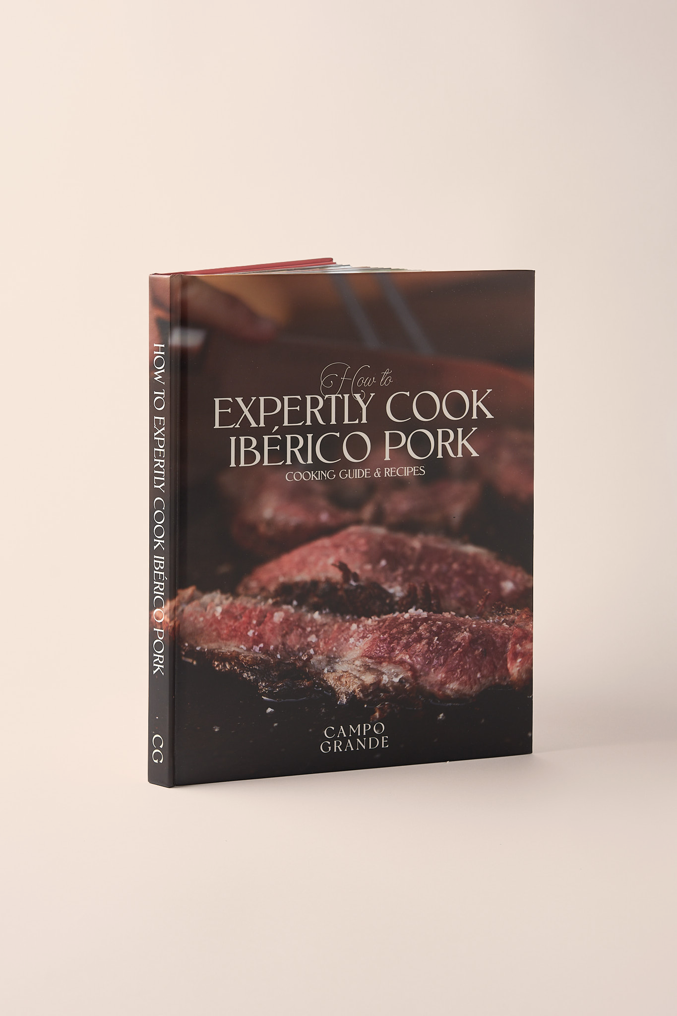 Hardcover cookbook titled "How to Expertly Cook Ibérico Pork" with cooked meat on cover and "Campo Grande" publisher name.