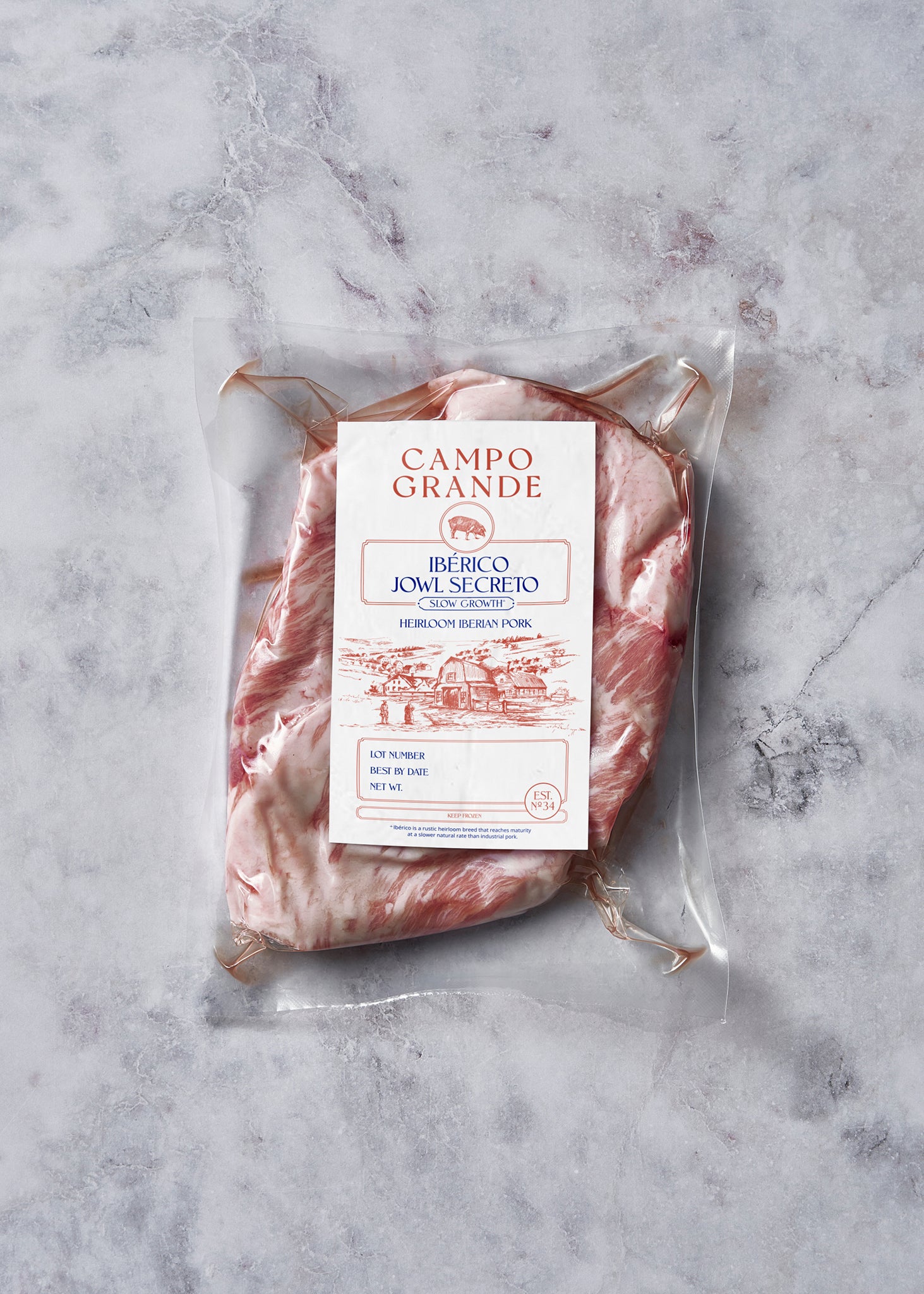 Packaged Ibérico jowl steak with marbled red and white meat, labeled Campo Grande, on gray textured surface.