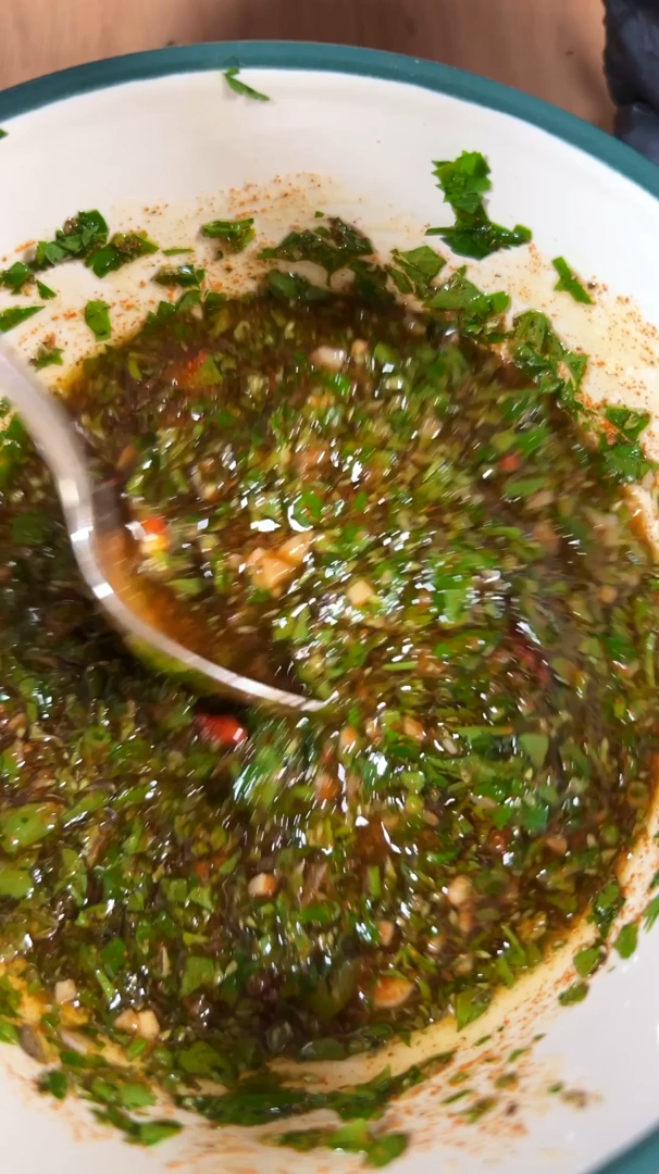 Herb chimichurri being stirred in a bowl